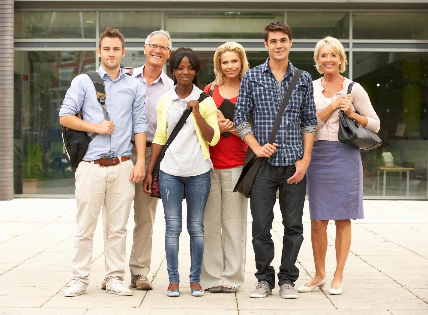 A smiling group of adult students standing together outdoors on a campus